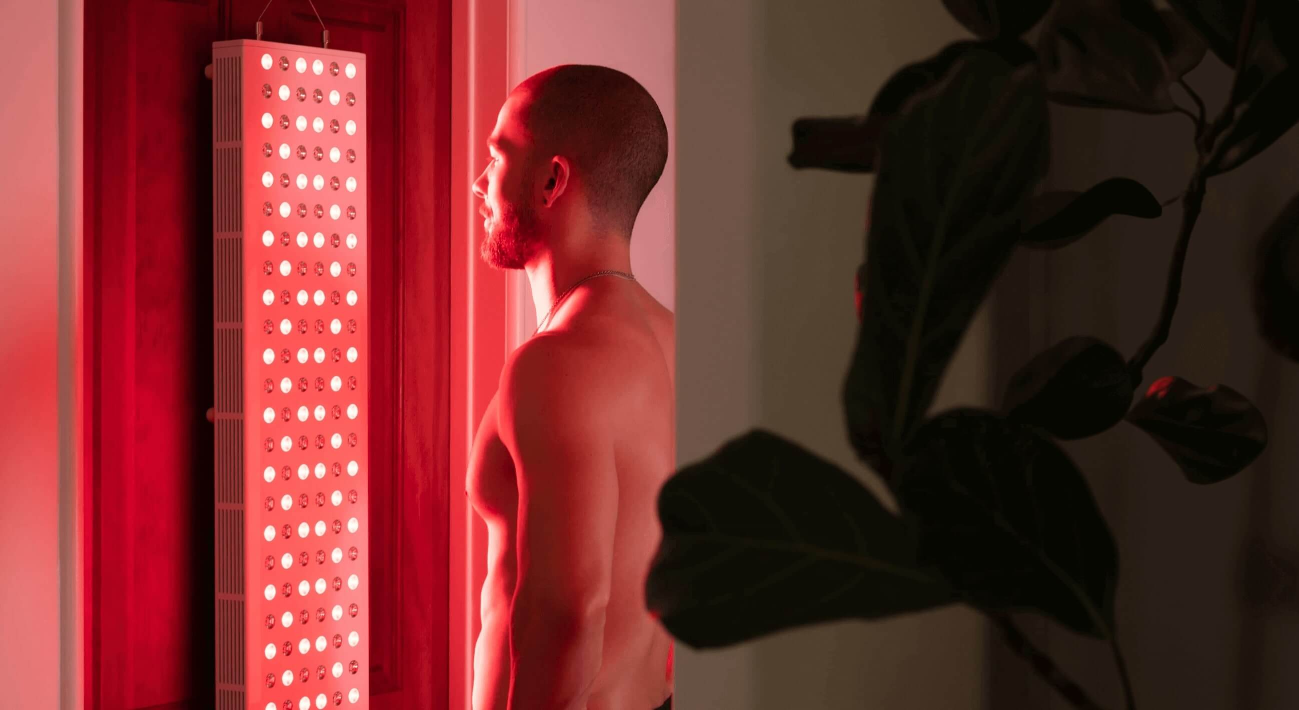 Man using red light therapy panel on his door