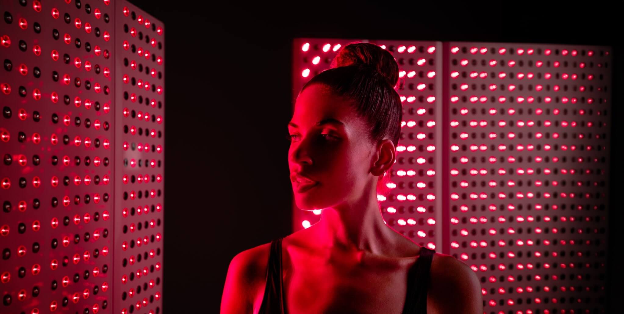 Lady standing infront of red light therapy panels
